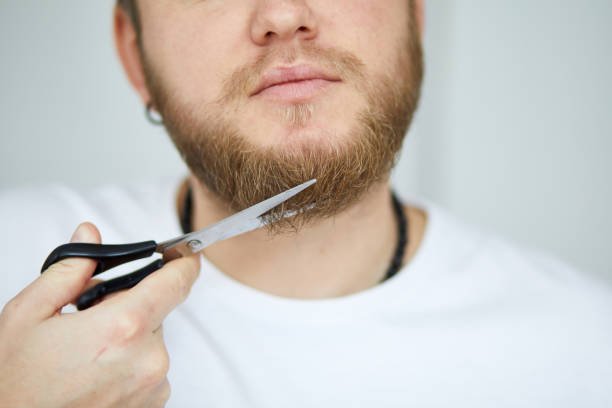 Man using a trimmer to shape his beard.